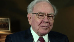 Warren Buffet, dono da Berkshire Hathaway, de terno preto e óculos, olhando para frente