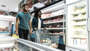 Casal de americanos dentro de supermercado olhando gôndolas, alusivo à inflação dos Estados Unidos