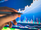 Caneta touch apontando para tela de gráficos de mercado financeiro, alusivo a onde investir em renda variável na semana