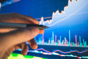 Caneta touch apontando para tela de gráficos de mercado financeiro