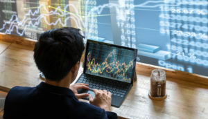 Investidor analisa gráfico financeiro em telas de computador