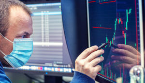 Investidor analisa gráficos financeiros em telas de computador
