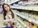 Mulher anota preços em supermercados
