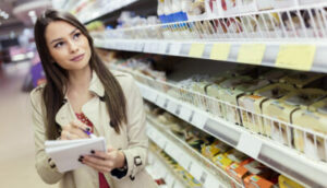 Mulher anota preços em supermercados