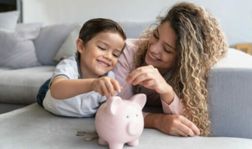 mãe e filho colocando uma moeda no cofre, alusivo a educação financeira infantil