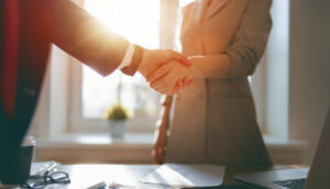 duas pessoas apertam as mãos, simulando um acordo para credenciar escritório de investimentos
